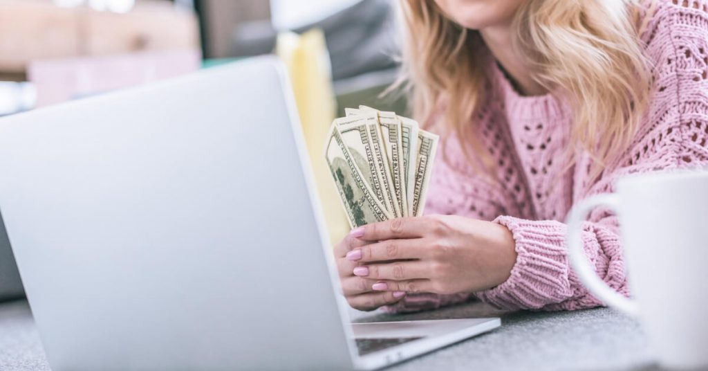 A woman who seems to be counting her money in front of her laptop