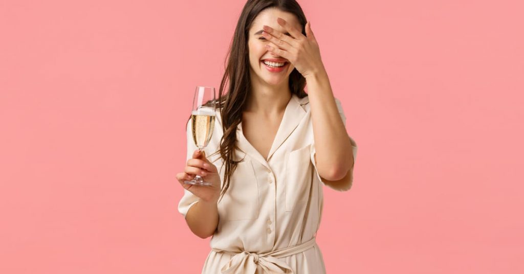 A girl holding a glass of drink and laughing