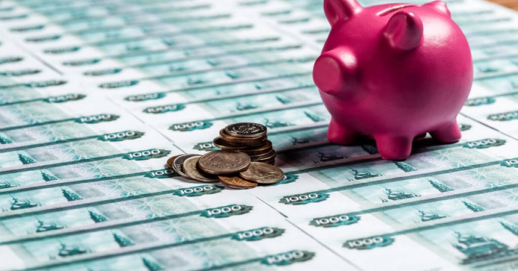 A pink piggy bank, coins, and thousand bills